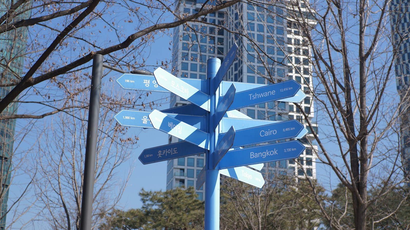 Blue Signpost With City Names Against Buildings Jigsaw Puzzle Free Online Jigsaw Puzzle